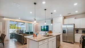 A modern kitchen with a central island, stainless steel appliances, and pendant lighting. - Luxury Villa w/ Pool & Disney Themes Solterra (Davenport)