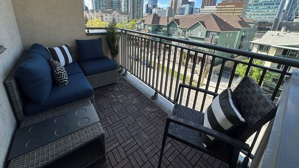 Un balcon avec un canapé et un fauteuil, une balustrade et une vue sur la ville.
