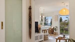 Una sala de estar moderna con televisor, zona de estar y vistas al exterior.
