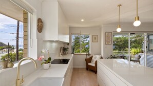 Una cocina moderna con un ventanal grande, armarios blancos y una estufa empotrada.