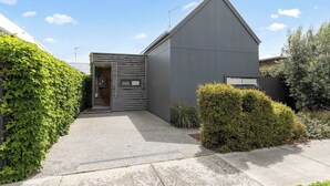 A modern two-story house with a sloped roof, a visible chimney, and a small front porch. - Spacious 1-bed Townhouse in Norlane (Geelong)