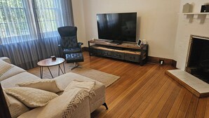 Una sala de estar con un televisor de pantalla plana grande, un sillón de cuero, un sofá y una chimenea.