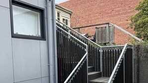 Una escalera con barandilla de metal que conduce a una cubierta de madera.