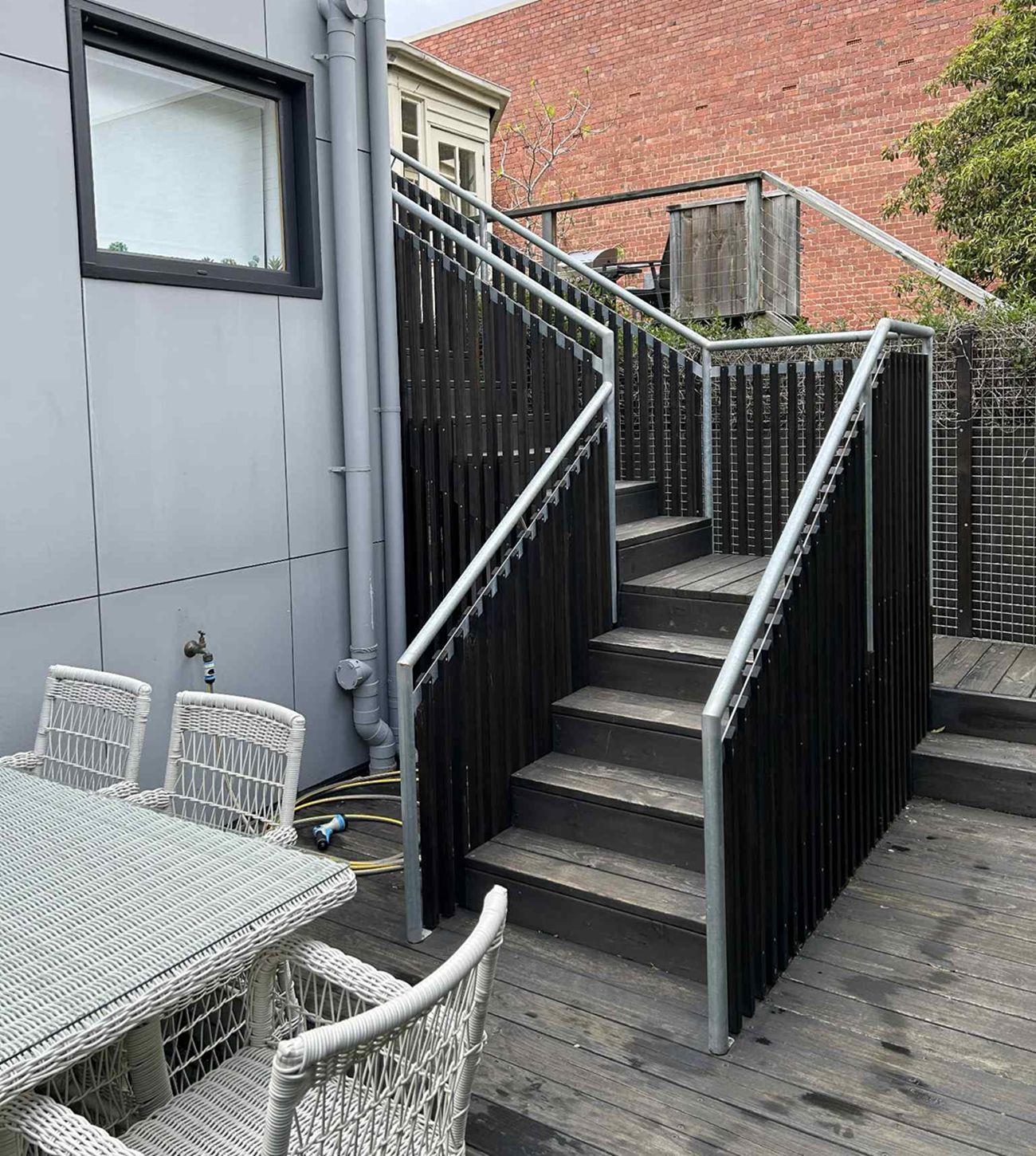 Uma escadaria com corrimão de metal que leva a um deck de madeira.