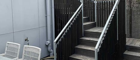 Un escalier avec une rampe métallique menant à une terrasse en bois.