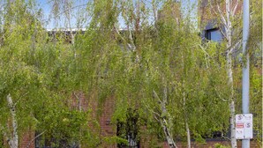 Un edificio de ladrillo con una puerta negra y una reja. Hay un cartel que indica una zona de cierre.