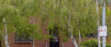 Un bâtiment en briques avec une porte noire et un portail. Un panneau indique une zone interdite d’accès.