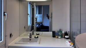 Ein kleines Badezimmer mit Waschbecken, Spiegel und Waschmaschine.