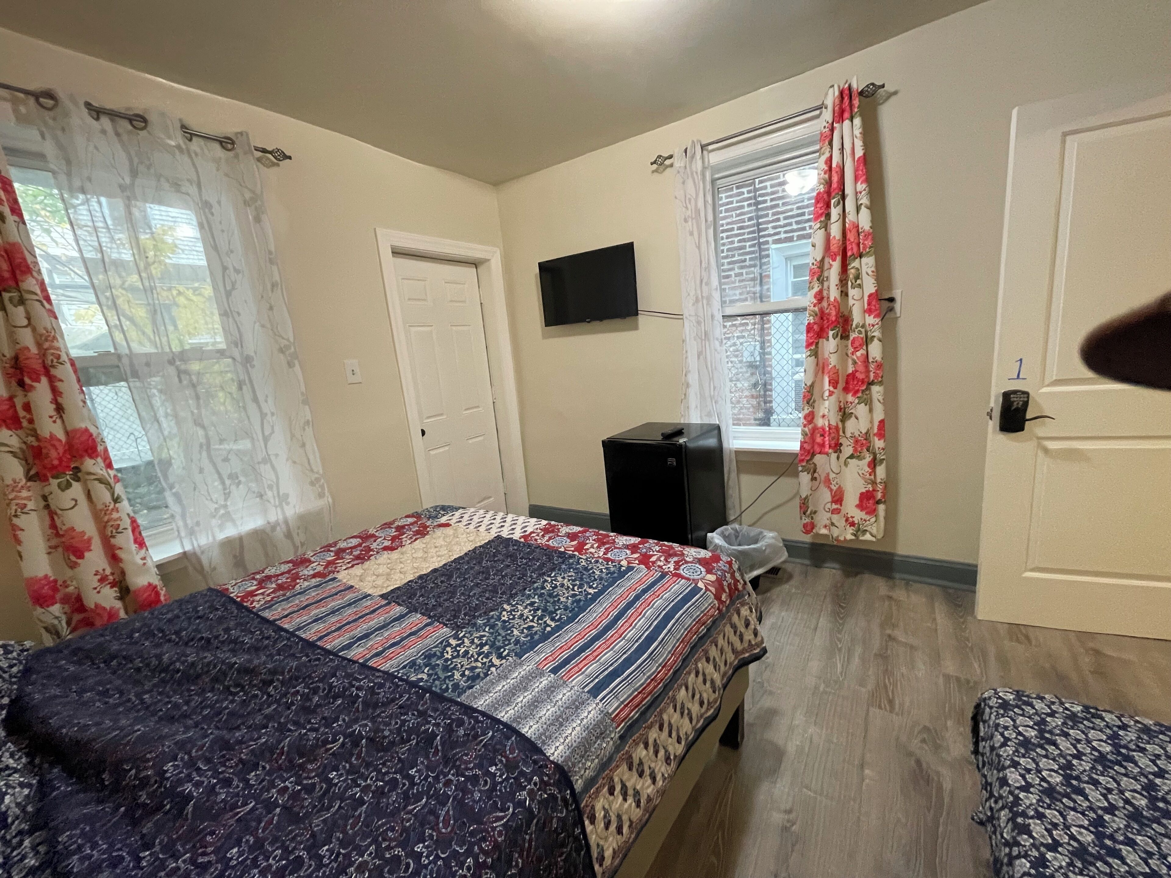 A room with a bed, a desk, a TV, and a window with curtains.