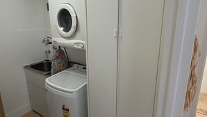 Een kleine wasruimte met een wasmachine, een droger en een klein wastafeltje.