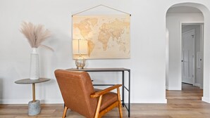 Una habitación moderna con un sillón de cuero marrón, una mesa redonda con una lámpara y un mapa mundial en la pared.