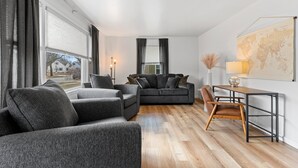 Una sala de estar moderna con un sofá gris, una mesa de centro de madera y un mapa en la pared.