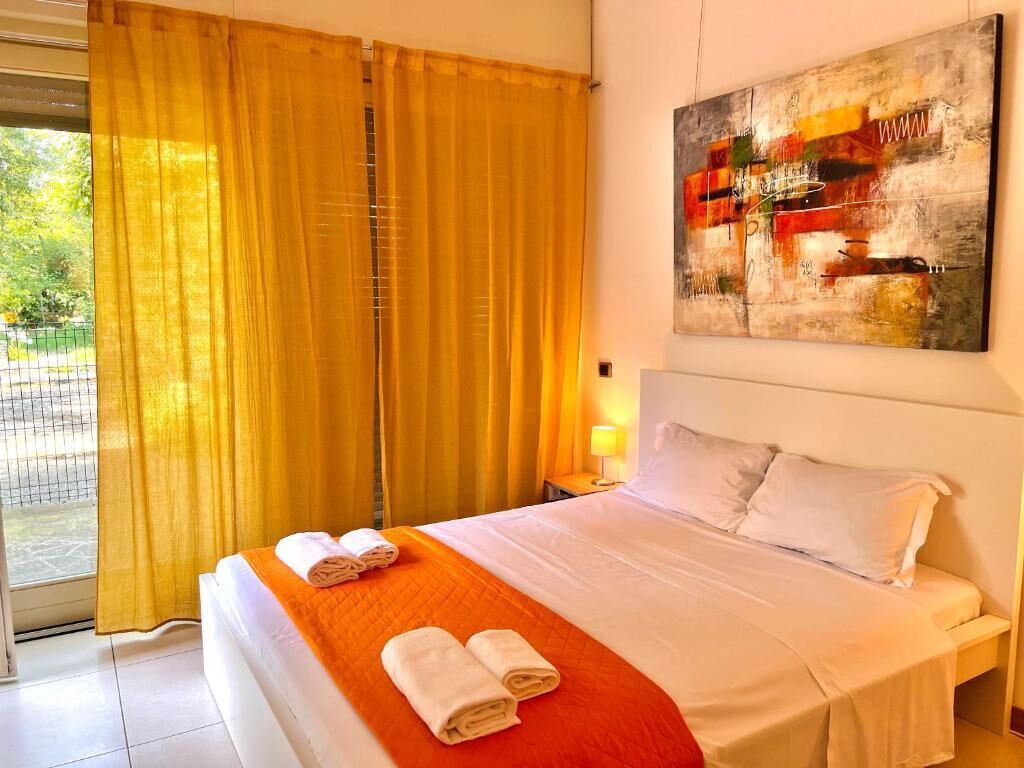 Une chambre d’hôtel avec un lit, un tableau au mur et une fenêtre avec des rideaux.