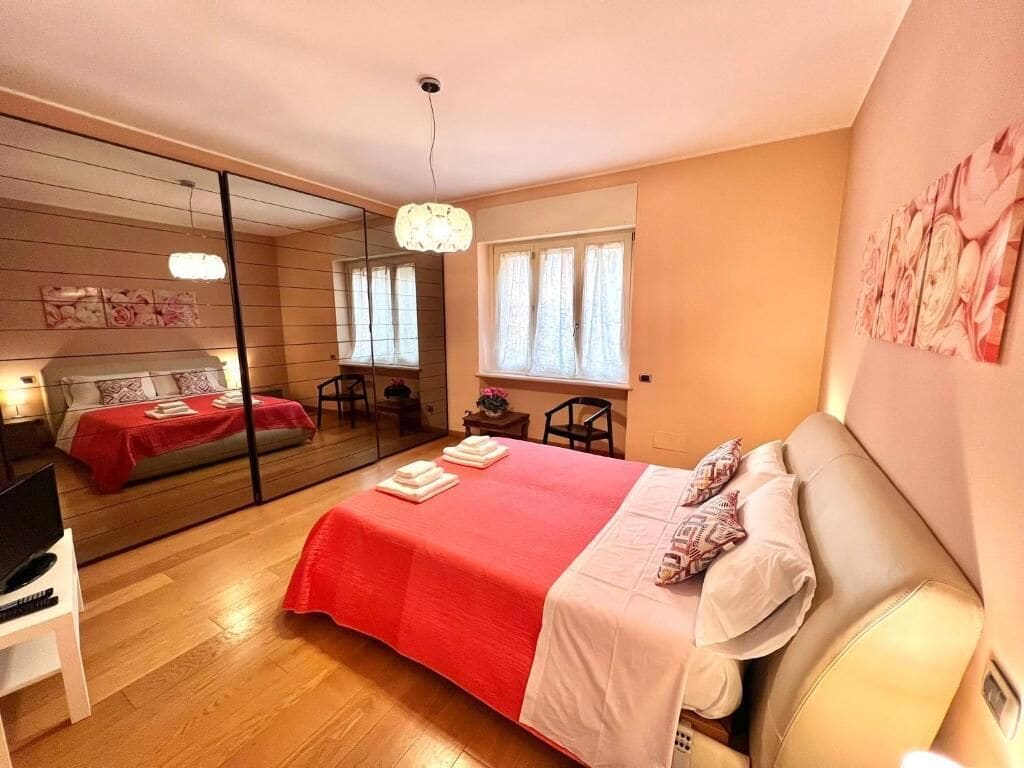 A bedroom with a large bed, a mirror, a desk, and a chair.