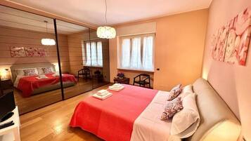 A bedroom with a large bed, a mirror, a desk, and a chair.