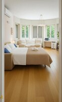 Una camera da letto moderna con un letto grande, una scrivania e vista sul verde attraverso le finestre.