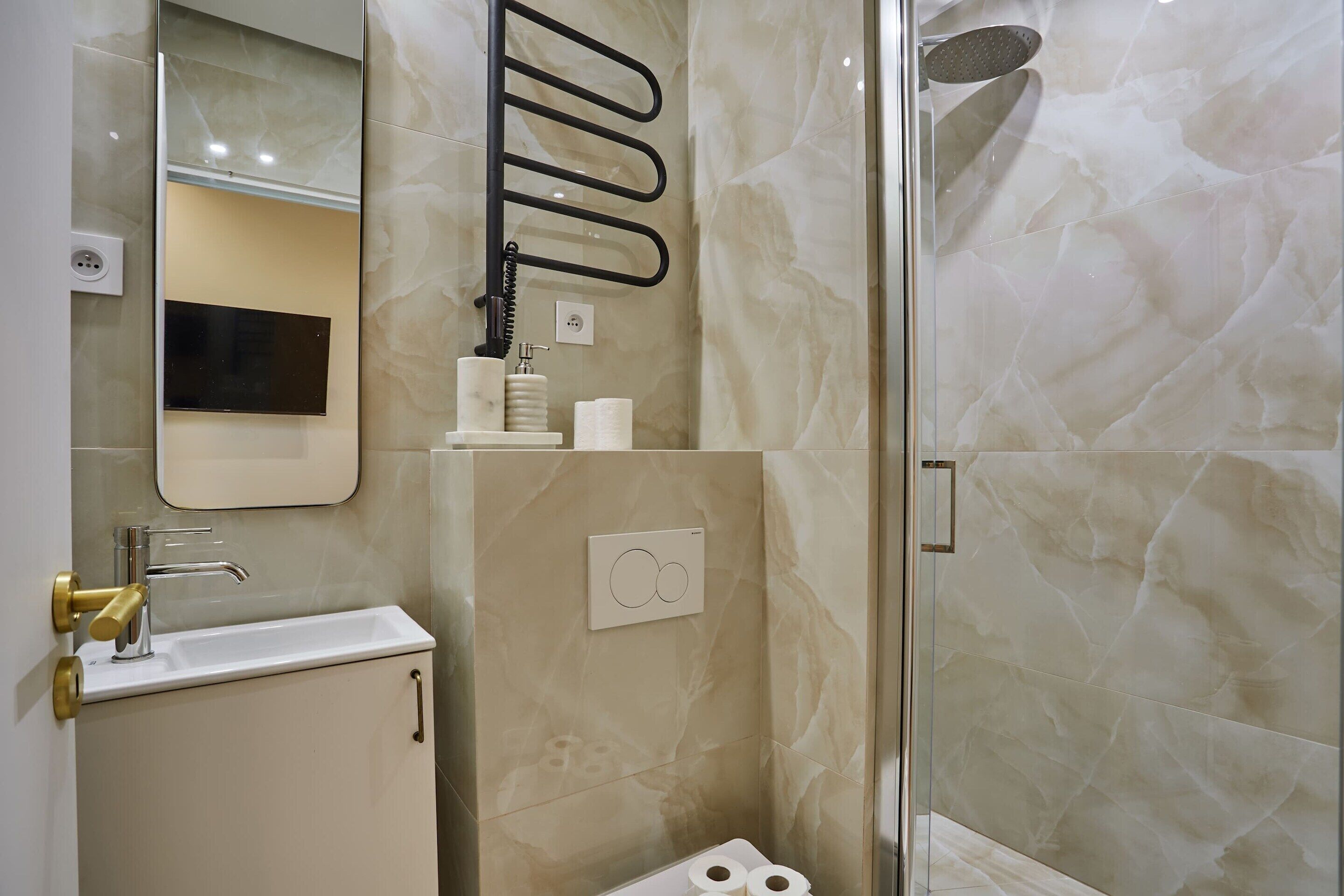A bathroom with a sink, mirror, towel rack, toilet, and shower.