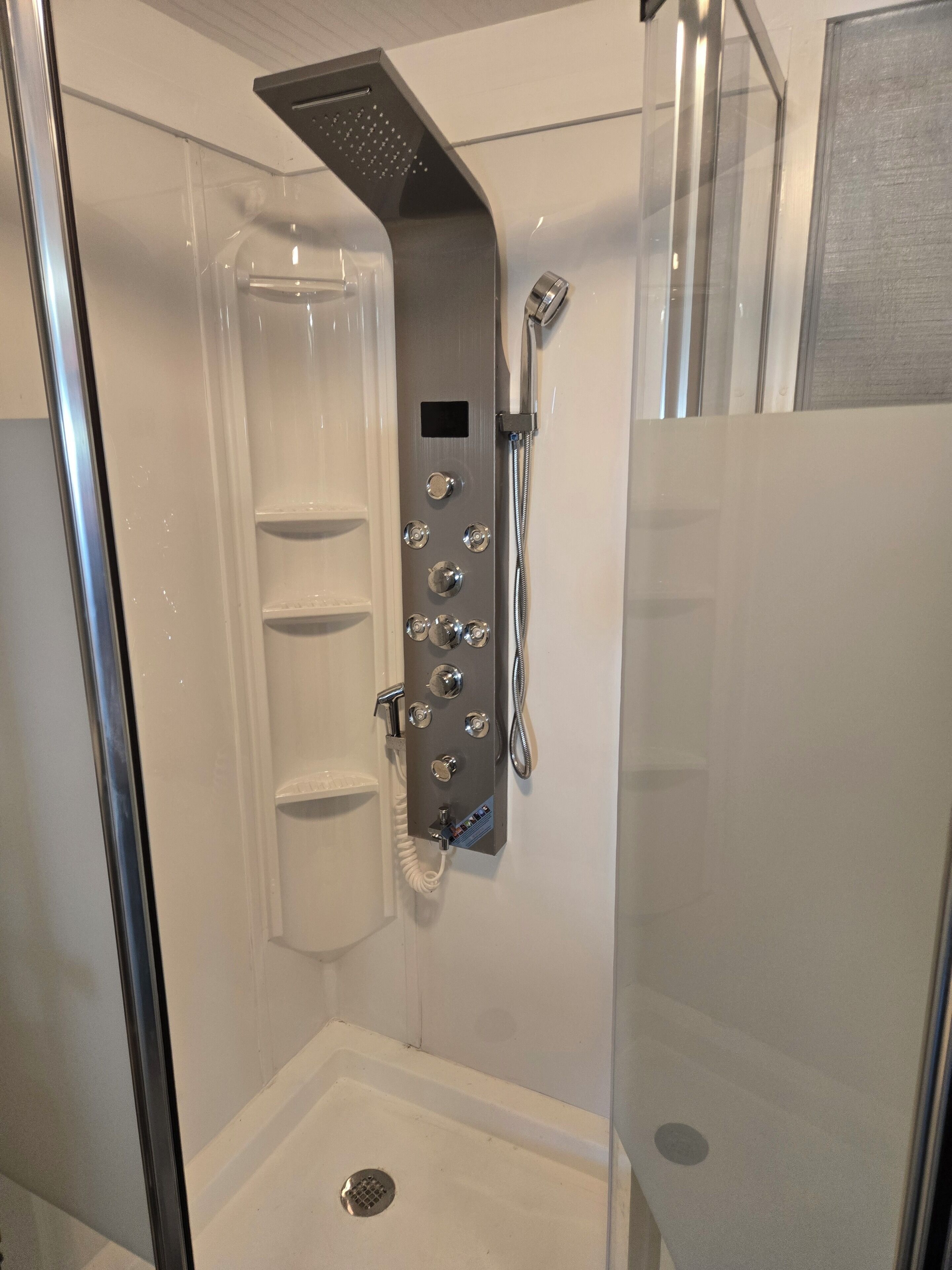 A modern shower with multiple controls and a handheld showerhead.