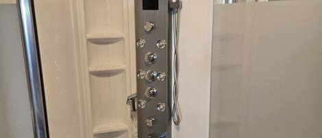 A modern shower with multiple controls and a handheld showerhead.