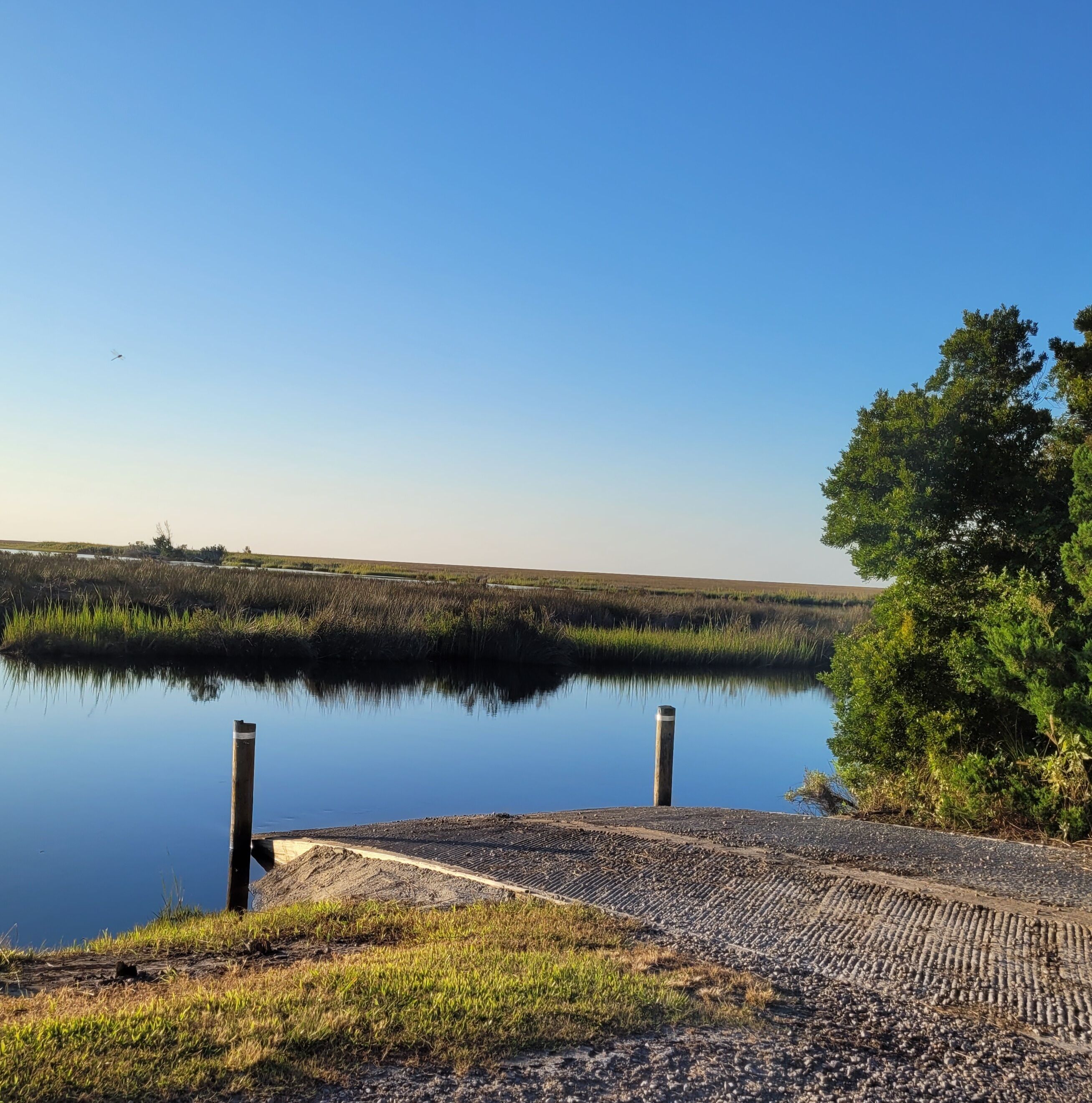 A calm lake with a dock and grassy banks.