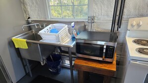 Una cocina pequeña con un lavamanos, un microondas y una estufa.