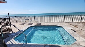 A rectangular swimming pool with a metal ladder, surrounded by a stone deck and a black metal fence. - “Sun, Sand & Spectacular Views Family-Friendly Madeira Beach Condo-Corner Unit (Madeira Beach)