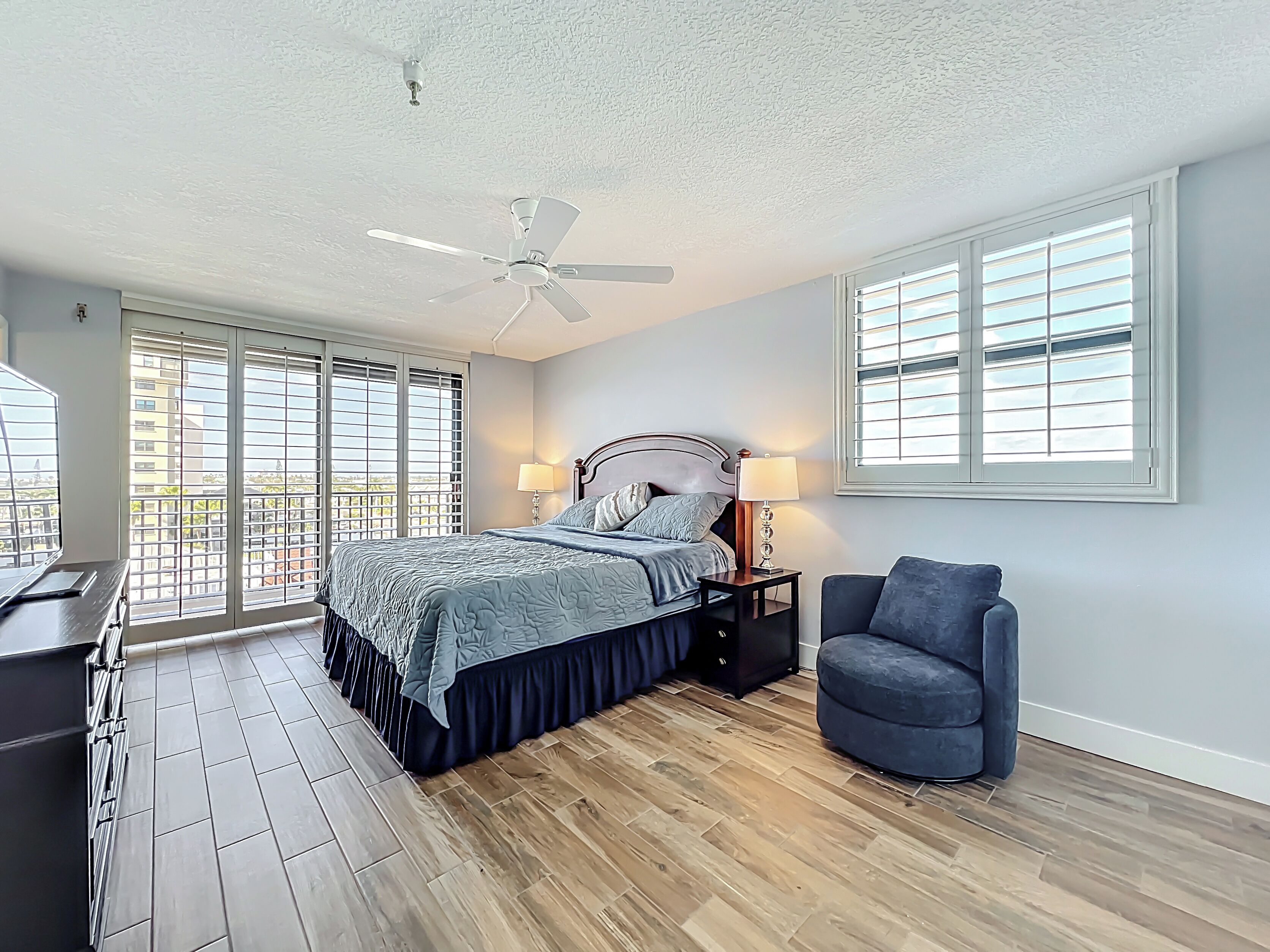 Ein Schlafzimmer mit Bett, Stuhl, Schreibtisch und Deckenventilator.