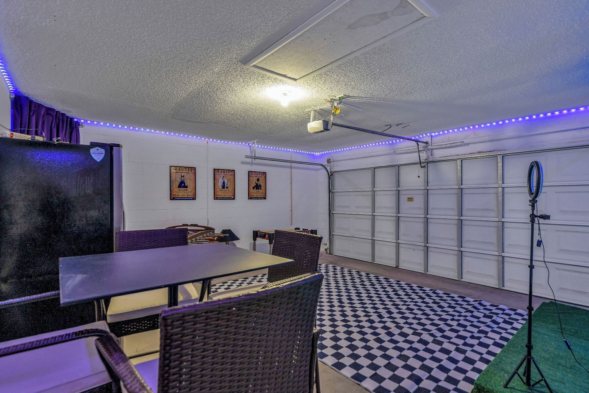 Un garage avec un sol à carreaux, une table, des chaises et un ventilateur de plafond.