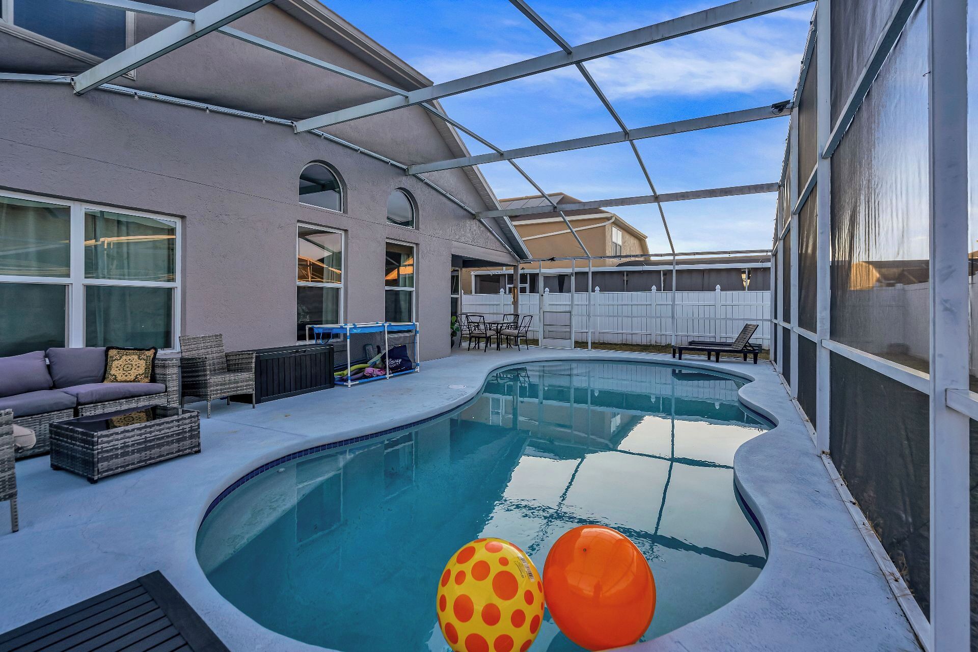 Ein überdachter Pool mit Terrassenbereich, Sitzgelegenheiten und einem umzäunten Garten.