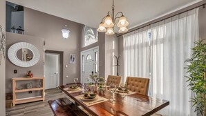 A dining area with a wooden table, cushioned chairs, and a chandelier. - Family 4BR Disney-Themed Home, Screened Pool, Game Room (Kissimmee)