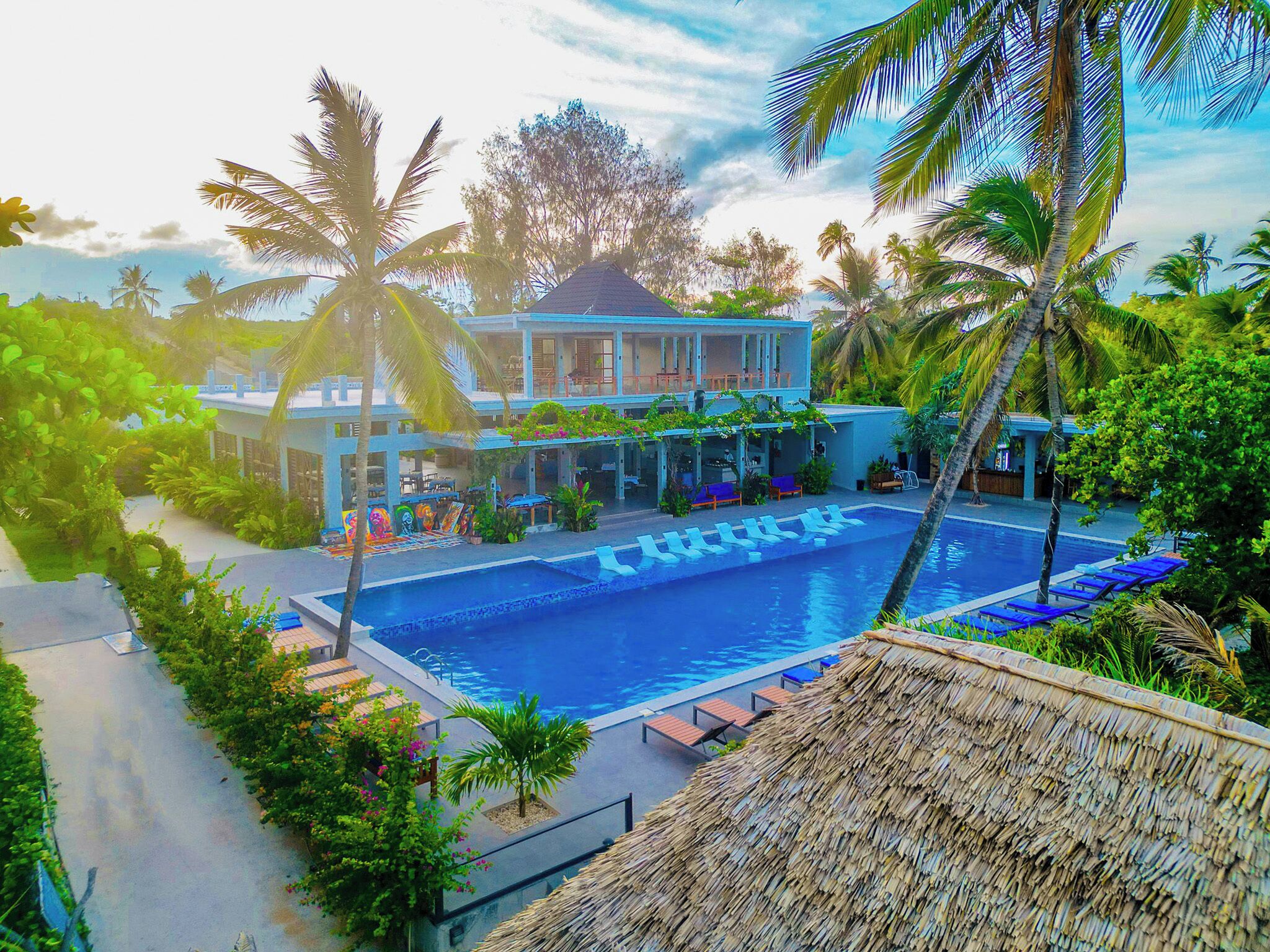 A resort with a swimming pool, lounge chairs, and tropical vegetation.