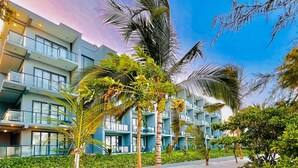 A modern hotel with a beachfront view, featuring multiple balconies, lush greenery, and a sandy walkway. - Matemwe Sands Beach Resort (Matemwe)