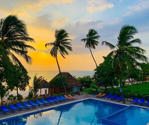 A poolside area with lounge chairs and a view of the ocean at sunset. -  Matemwe Sands Beach Resort (Matemwe)