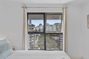 A bedroom with a large window, a bed, and a view of buildings. - Central Studio in Kangaroo Point (Brisbane)