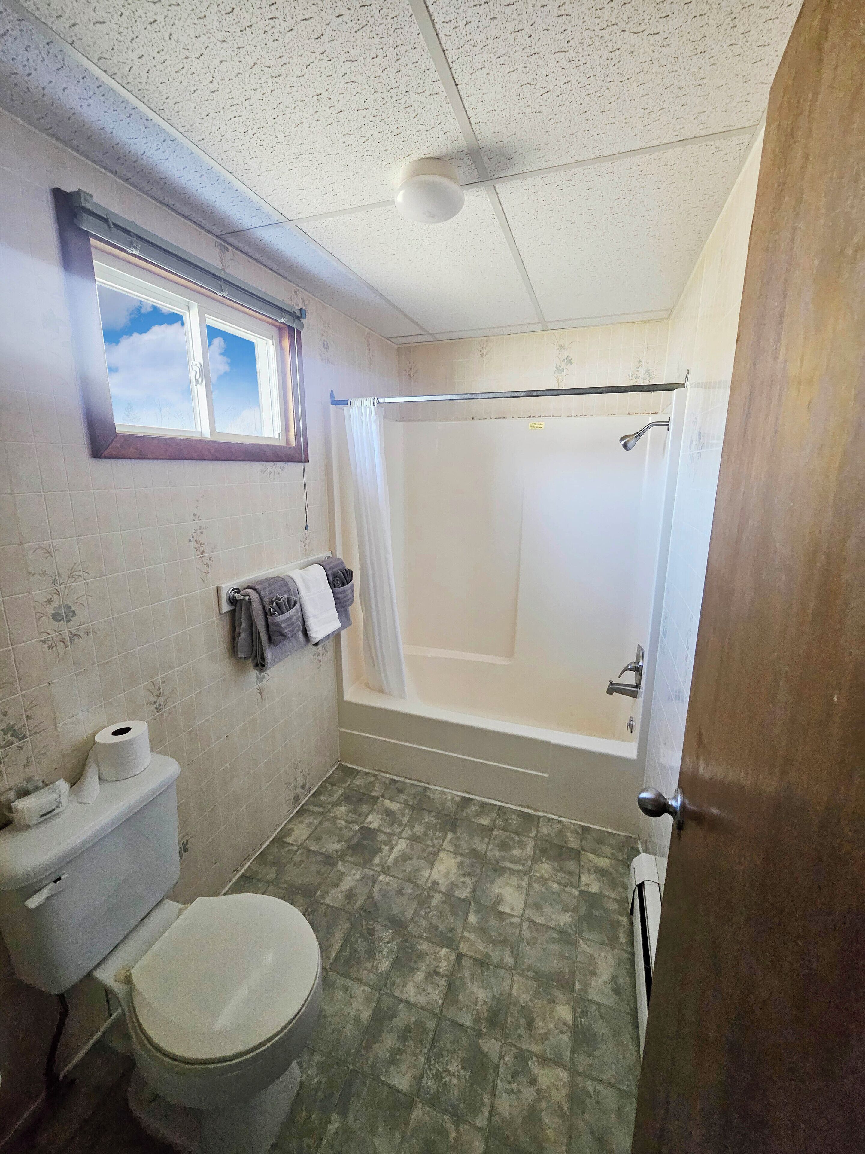 Ein kleines Badezimmer mit Toilette, Dusche und Fenster.
