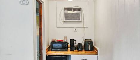 A compact kitchen with a microwave, toaster, and coffee maker on a wooden countertop.