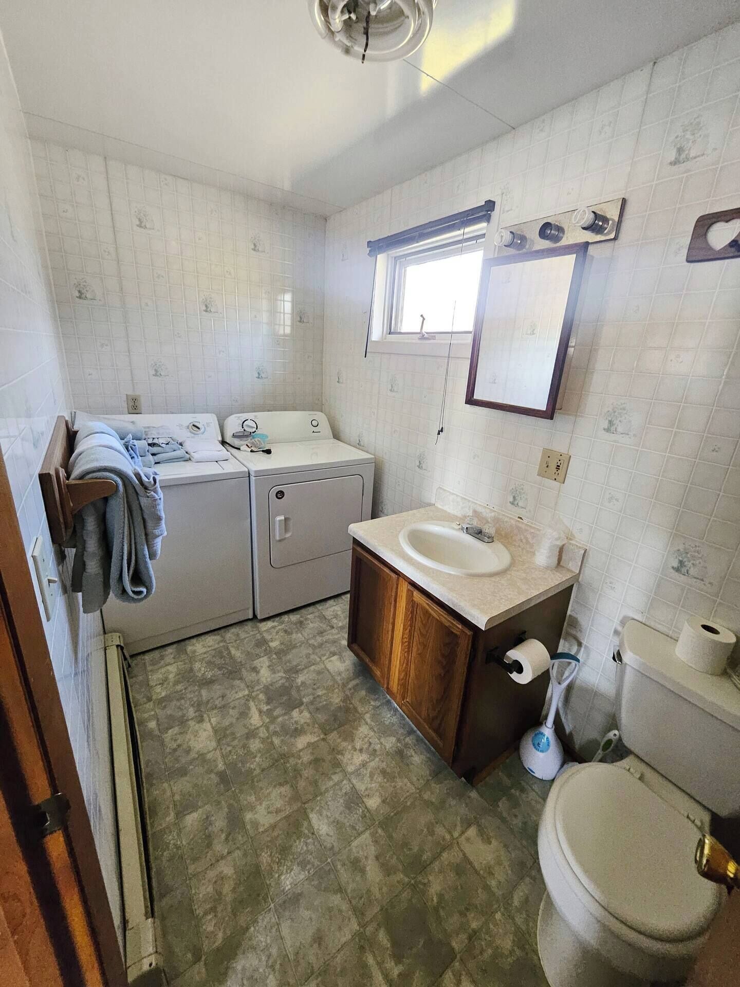 Un baño pequeño con lavadora, lavamanos e inodoro.
