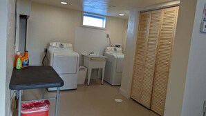 A laundry room with two washing machines, a sink, and a table with cleaning supplies.