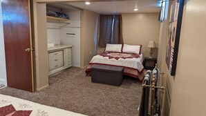 A bedroom with a bed, a dresser, a closet, and a window with curtains.