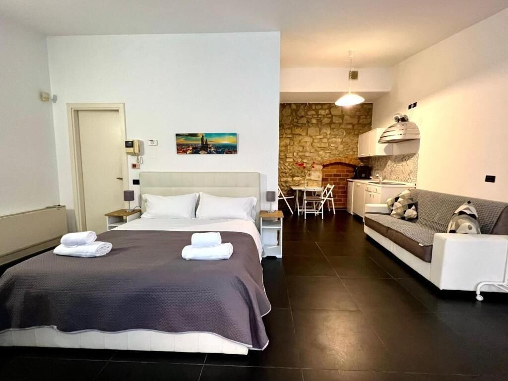 A hotel room with a bed, a sofa, a dining area, and a kitchen.