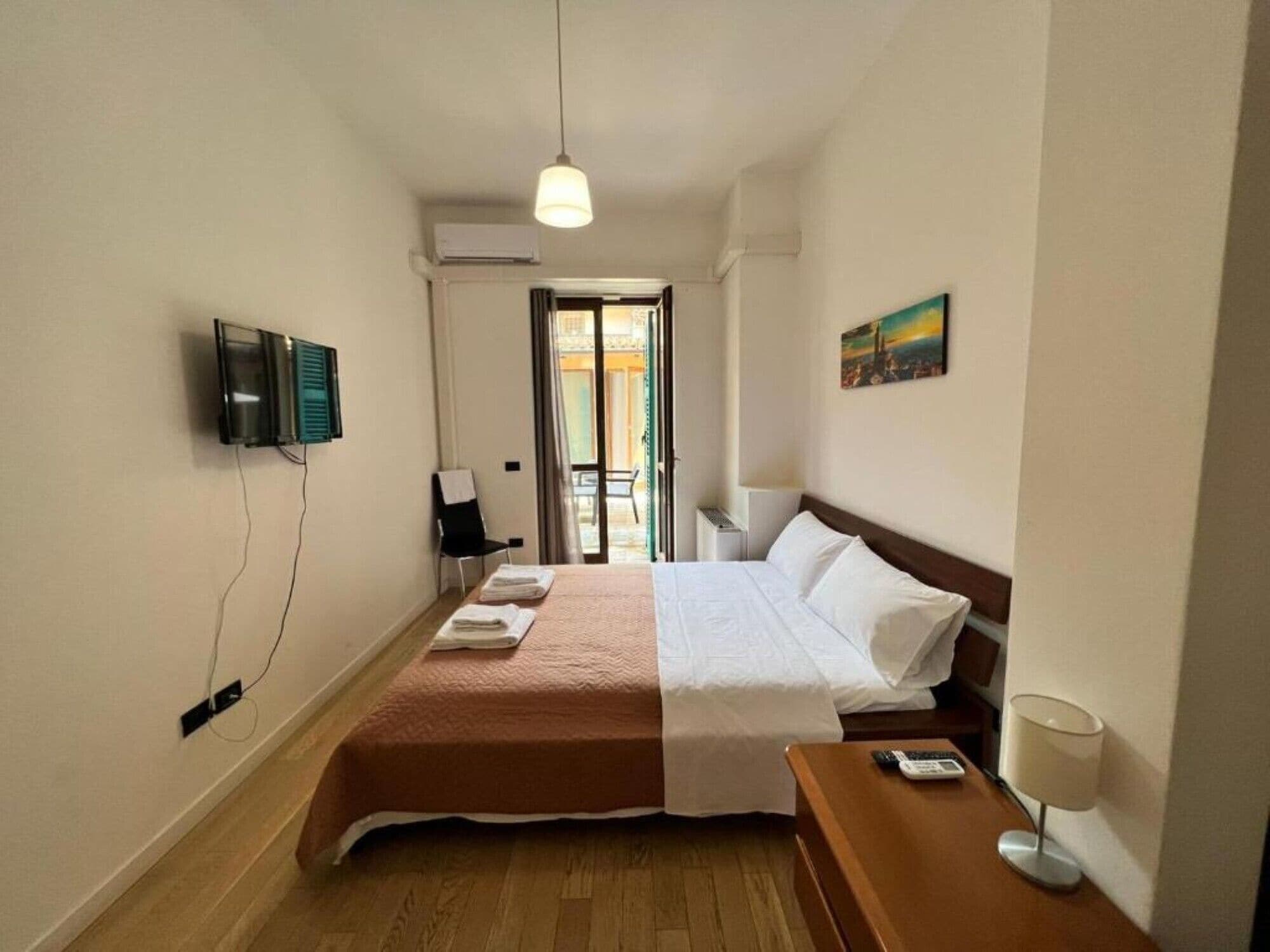 Une chambre d’hôtel avec un lit, un bureau doté d’une lampe, une télévision et un tableau accroché au mur.