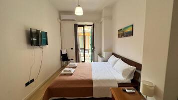 Une chambre d’hôtel avec un lit, un bureau doté d’une lampe, une télévision et un tableau accroché au mur.
