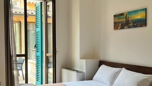A hotel room with a bed, a painting on the wall, and a view through an open door. - Bergamoincenter (Bergamo)