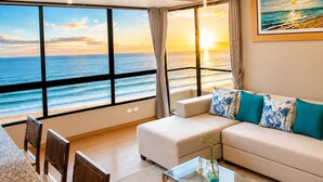 Una stanza con una grande finestra vista mare, un divano con cuscini decorati, un tavolino da caffè in vetro e un quadro appeso al muro.