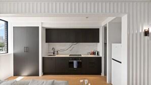 Eine moderne Küche mit dunklen Schränken, einer Marmor-Spritzschutzwand und einem eingebauten Backofen.