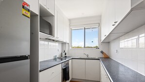 Cocina moderna con armarios blancos, encimera negra y ventana que proporciona luz natural.