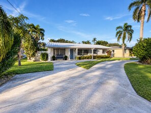 A two-story house with a covered porch, a driveway, and a well-maintained lawn.