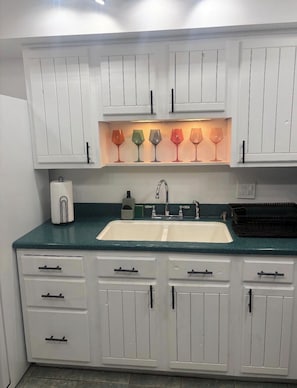 A kitchen with white cabinets, a double sink, and a countertop with various items.