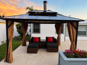 Un espacio de estar al aire libre techado con dos bancos acolchados y una pérgola.