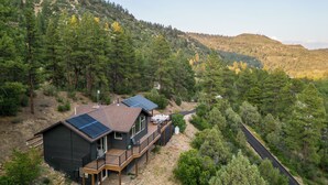 A modern house with a deck, surrounded by dense forest and hills. - Breathtaking View 12 Min to Downtown (Durango)